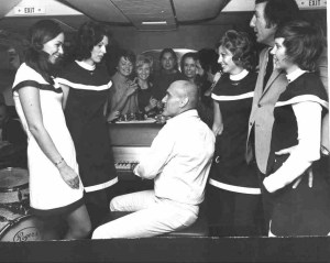 Airline stewards talking to a man playing a piano on a 747.