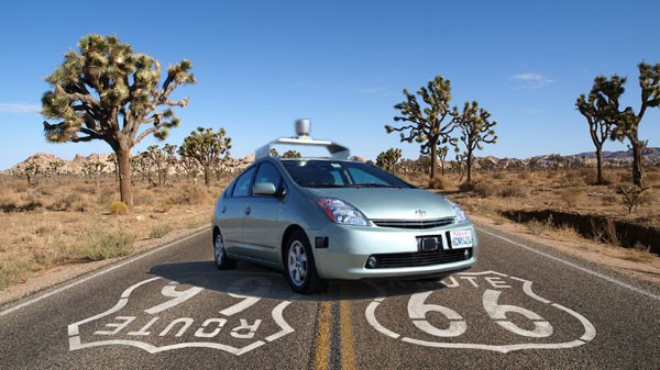 A google driverless car on a stretch of route 66, in the desert. The car is stationary and facing the camera in a posed shot.